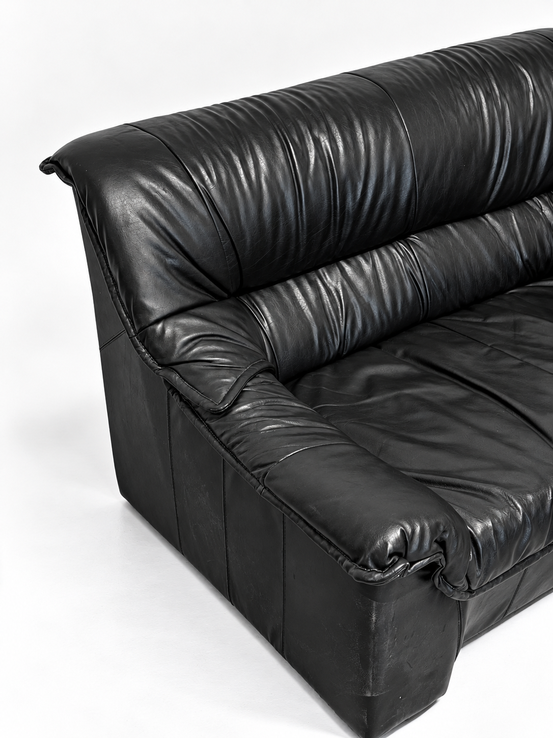 Black leather two-seater sofa, armrest detail